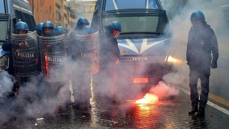 A policeman clears away a flare during a confrontation with students in Rome, 15 November