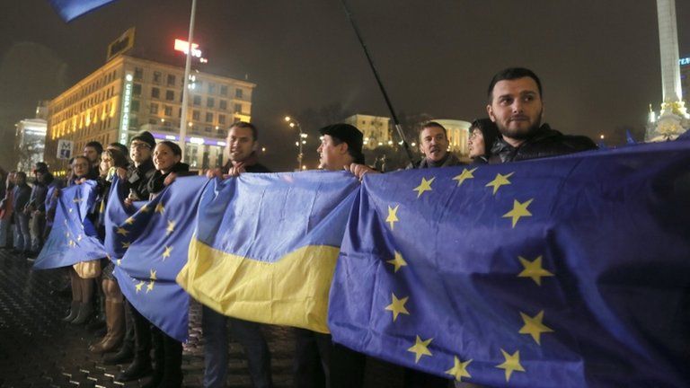 Activists wave Ukrainian and European Union flags during a night rally in support of Ukraine's integration with the European Union in Kiev