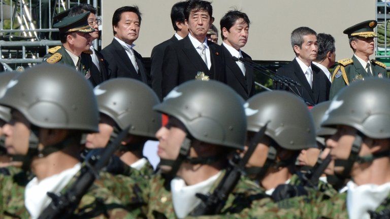 Japanese Prime Minister Shinzo Abe (top C) inspecting troops in Tokyo on 27 October 2013