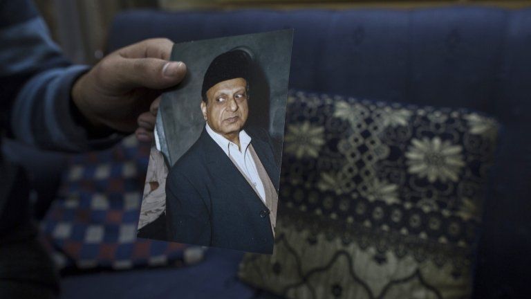 A photograph of Masood Ahmad is held by his nephew at his house in Lahore December 10, 2013