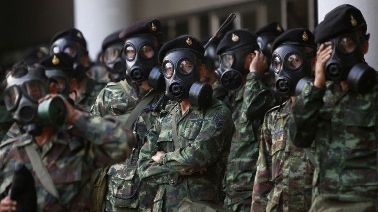 Soldiers wear gas masks as they stand guard at the Thai-Japan youth stadium in central Bangkok, 26 December 2013
