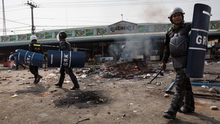 Police walk past a fire during a demonstration on 3 January 2014 in Phnom Penh, Cambodia