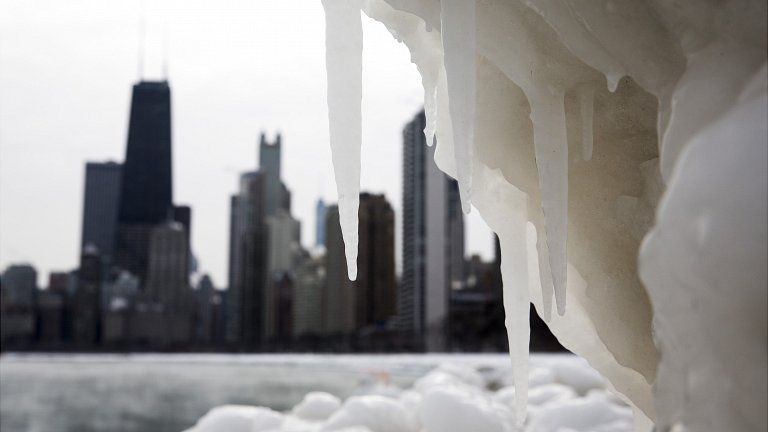 The Chicago skyline is photographed behind a large chunk of ice near North Avenue Beach as freezing temperatures remain