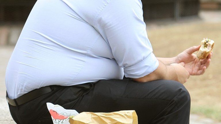 Overweight man eating fast food