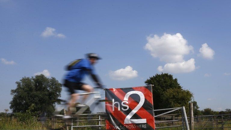 A man cycles past an anti high speed rail project (HS2) banner in Austrey, central England