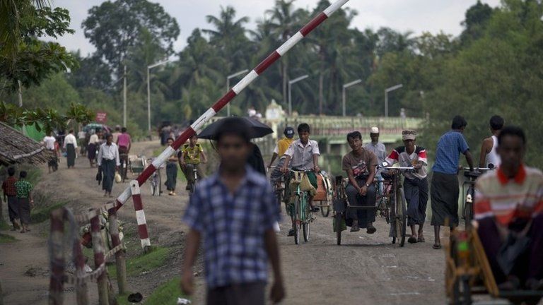 In this Sept. 14, 2013 photo, Muslims travel past a road barrier next to a security checkpoint in Maungdaw, northern Rakhine state, Myanmar.