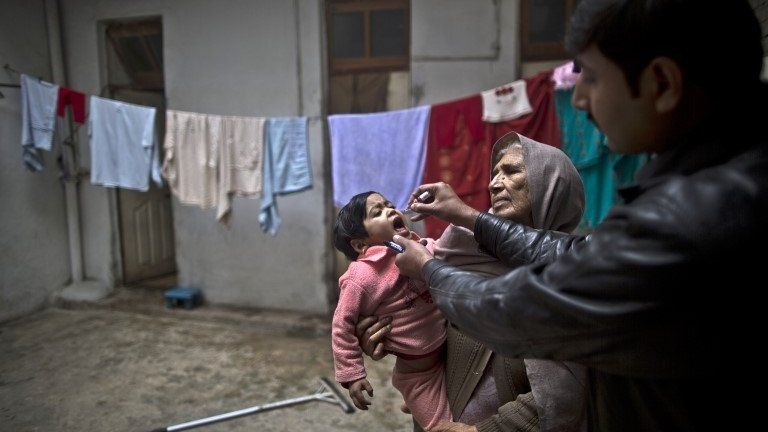 A Pakistani health worker, right, gives a polio vaccine to a child held by her grandmother at their home in Rawalpindi, Pakistan, Monday, Jan. 20, 2014.