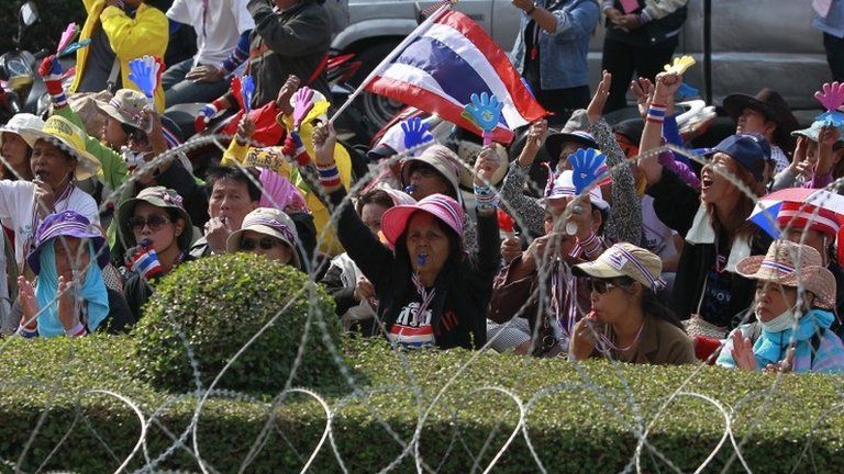 Anti-government protesters gestures next to a wire barricade during a rally outside the Permanent Secretary of Defense in Bangkok, 22 January 2014