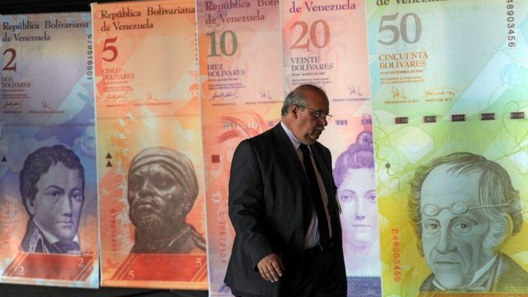 A man walk in front of posters of Venezuelan bills in Caracas