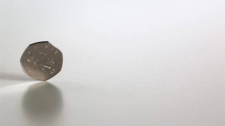 A 50p coin on its edge on a white background