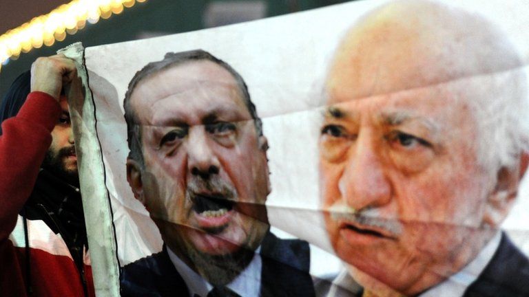 A Turkish anti-government protester (L) holds up a banner with pictures of Turkish Prime Minister Recep Tayyip Erdogan (C) and the Islamic cleric Fethullah Gulen (R)