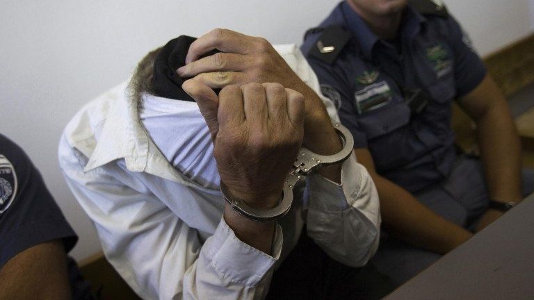 Yitzhak Bergel attempts to conceal his identity during a court appearance in Jerusalem in August 2013