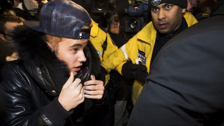 Canadian musician Justin Bieber is swarmed by media and police officers as he turns himself into city police for an expected assault charge, in Toronto, 29 January 2014