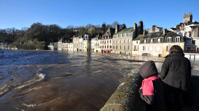 A woman and a child look at a flooded street in the centre of Quimperle, western France, 7 February