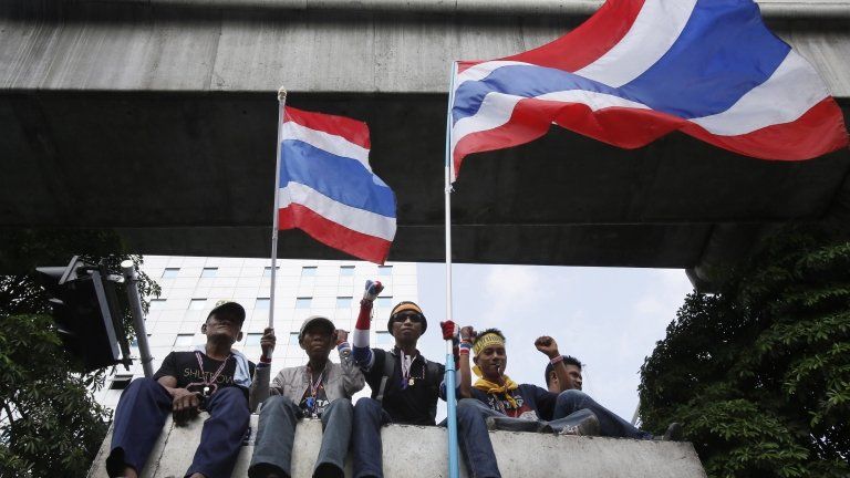 Anti-government protesters wave Thai national flags as they ride on the roof of a truck parading through central Bangkok, Thailand, on 7 February 2014
