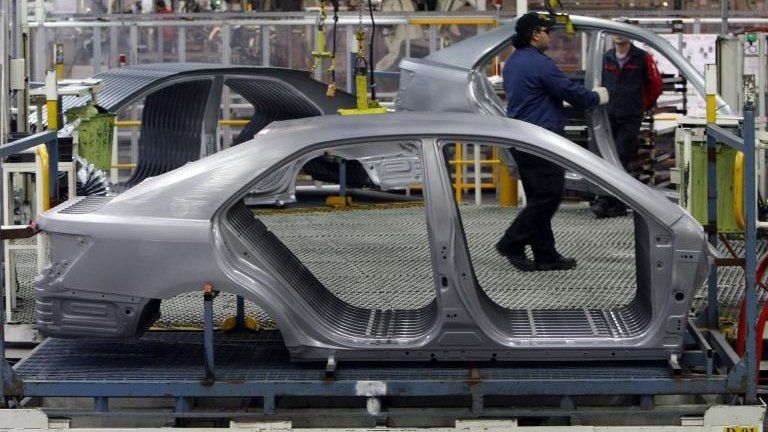 An auto worker loads bodyshells of a Toyota Camry Hybrid car onto the assembly line at the Toyota plant in Melbourne