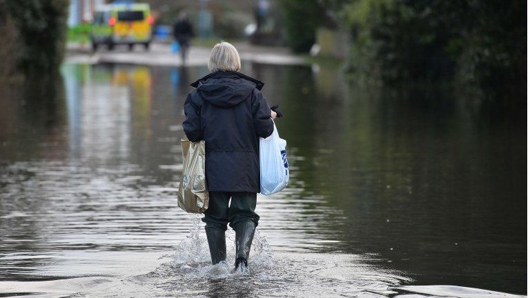 A woman walks through floodwater in Wraysbury, west of London