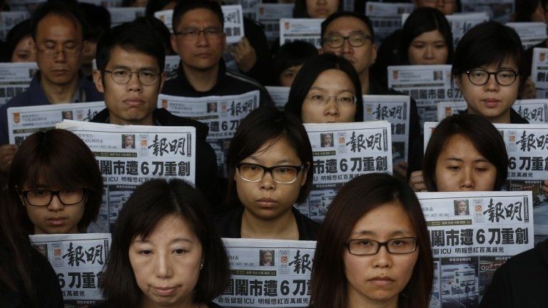 Editorial staff members of the Ming Pao newspaper hold the front page of their newspaper outside the Ming Pao office in Hong Kong, 27 February 2014