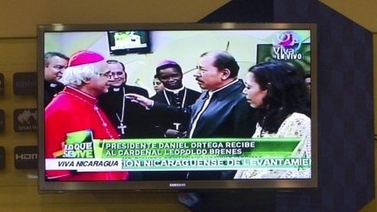 A TV screen shows live coverage of Nicaragua's President Daniel Ortega (centre) and his wife Rosario Murillo welcoming home Nicaragua's newly-appointed Cardinal Leopoldo Brenes