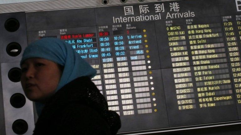 Woman in front of arrivals board at Beijing airport, China (8 March 2014)