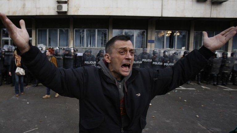 A Bosnian man gestures with his hands as he urges other protesters to stop stoning a local government building in Bosnian town of Tuzla on 6 February