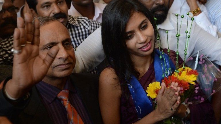 Indian diplomat Devyani Khobragade (R), accompanied by her father Uttam Khobragade, gives a traditional greeting on her arrival at the domestic airport in Mumbai 14 January 2014