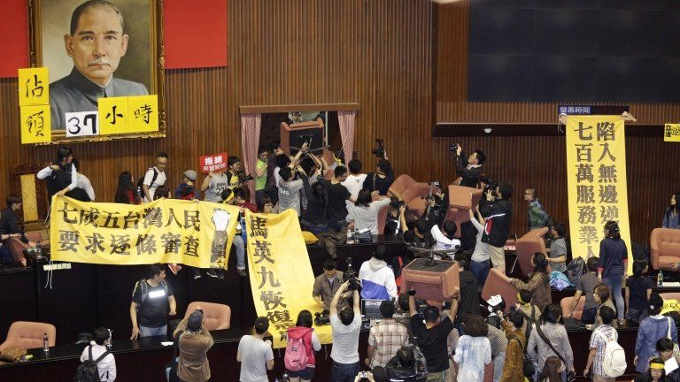 Students and protesters hold banners and chairs inside Taiwan's legislature in Taipei on 18 March 2014