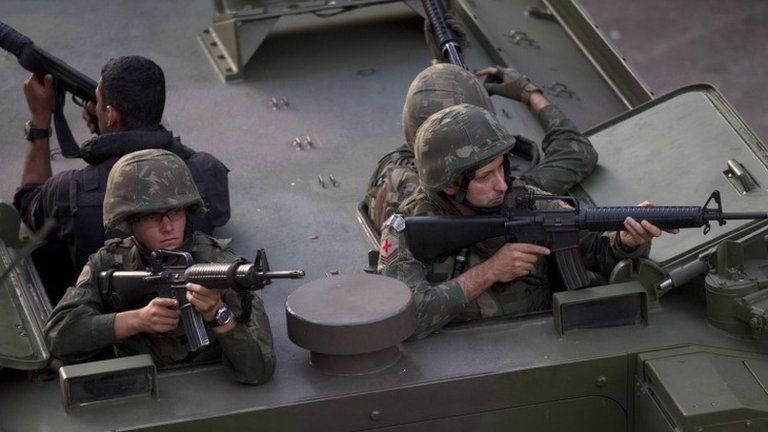 Brazilian soldiers take position during an operation to occupy the Mare slum complex in Rio, 30 March