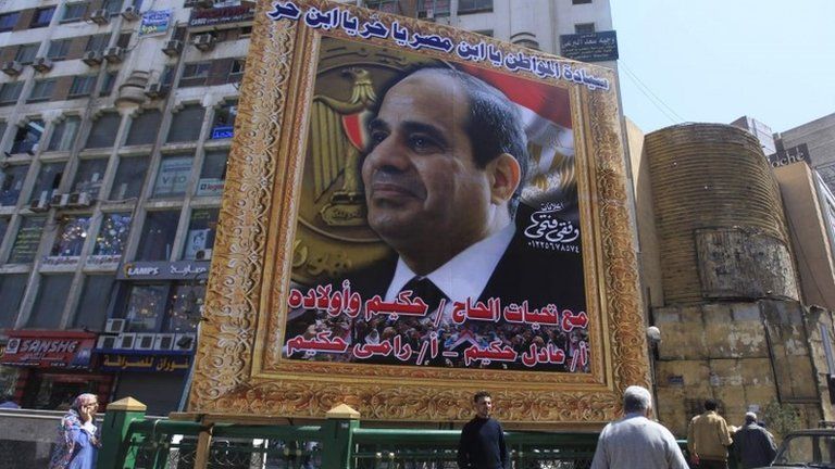 People stand under a huge banner of Egypt"s former army chief Abdel Fattah al-Sisi in downtown Cairo