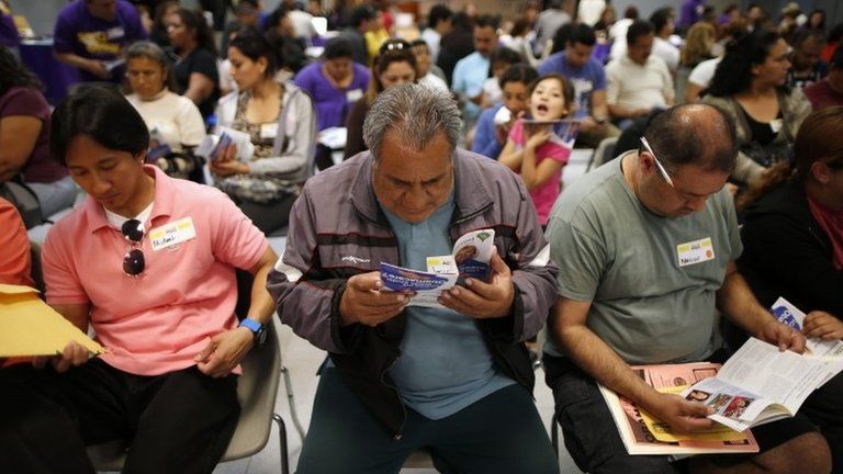 Jesus Dominguez who does not have health insurance, reads a pamphlet at a health insurance enrolment event in Cudahy, California 27 March 2014