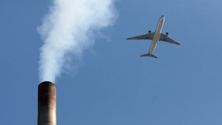 Plane flies over chimney stack