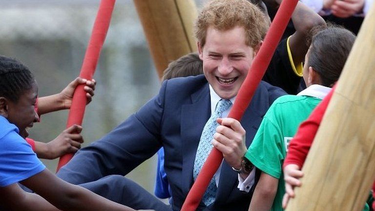 Prince Harry sits on a swing during a visit to the new Queen Elizabeth Olympic Park