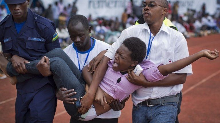 A wailing and distraught Rwandan woman, one of dozens overcome by grief at recalling the horror of the genocide, is carried away to receive help during a public ceremony to mark the 20th anniversary of the Rwandan genocide, at Amahoro stadium in Kigali, Rwanda Monday, April 7, 2014.