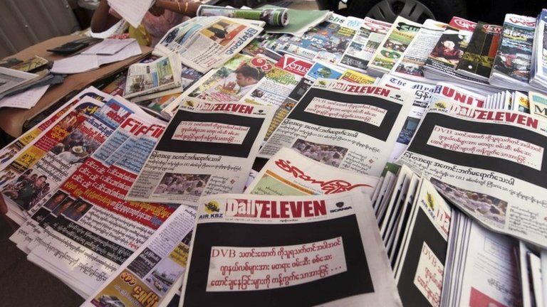 A vendor sits by local weekly news journals with their front pages printed black with letters saying "By opposing recent arrest and sentencing of journalists including a video journalist of DVB (Democratic Voice of Burma)" at a roadside shop Friday, 11 April 2014, in Yangon, Myanmar