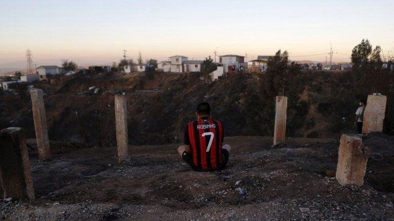 A resident, who lost his home, sits on the edge of a hill where a fire burned several neighbourhoods in Valparaiso city on 14 April, 2014.