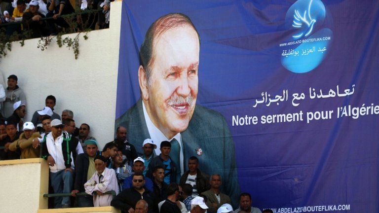 Supporters of Algerian President and presidential candidate Abdelaziz Bouteflika stand in front of his poster during a rally meeting in Annaba, east of Algiers