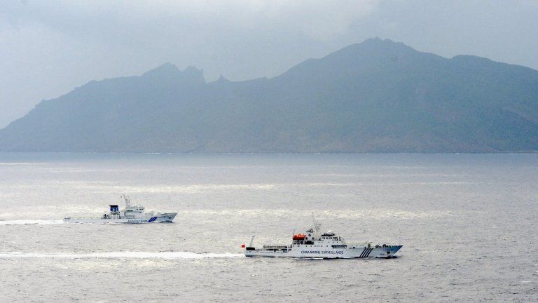 In this 23 April 2013 file photo, a Japan Coast Guard vessel (L) sails along with a Chinese surveillance ship near the disputed islands