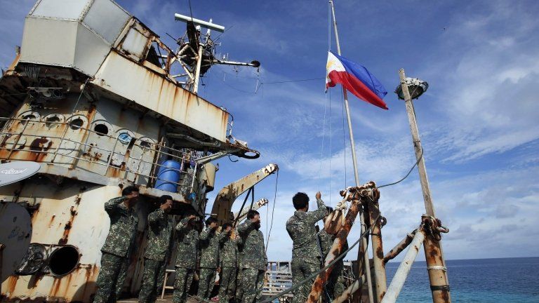 Marines stationed aboard a Philippine ship grounded on a disputed reef, the Second Thomas Shoal, take part in a flag ceremony on 29 March 2014