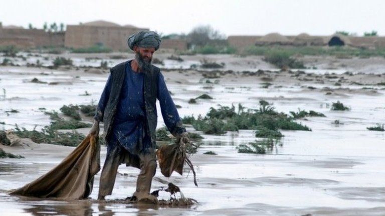 An Afghan man carries his belongings over wet ground after a flood at Jowzjan province northern Afghanistan