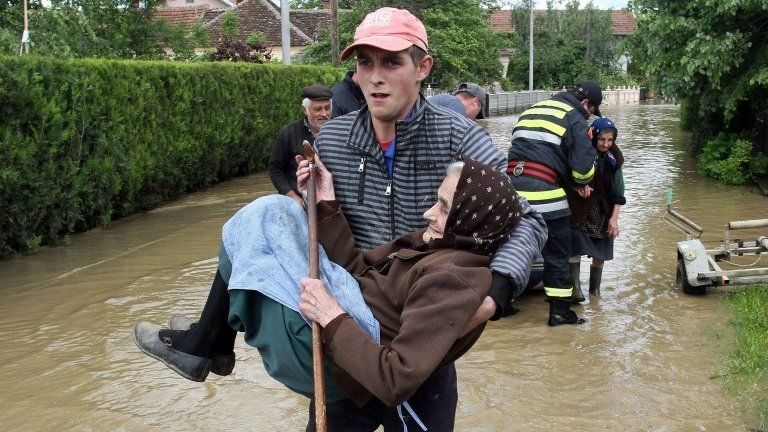 A Serbian rescuer carries an elderly woman in the village of Obrez, south of Belgrade, on 17 May 2014.