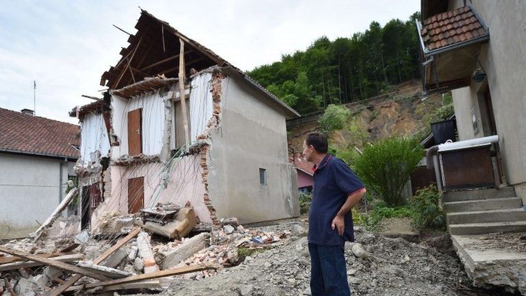 A man stands near his house damaged by flooding and a landslide in Krupanj, Serbia