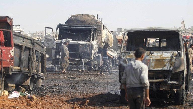 File photo: People walk near burnt trucks and fuel tankers at a fuel market hit by a car bomb in the Maarat Al-Naasan area of Idlib, Syria, 28 May 2014