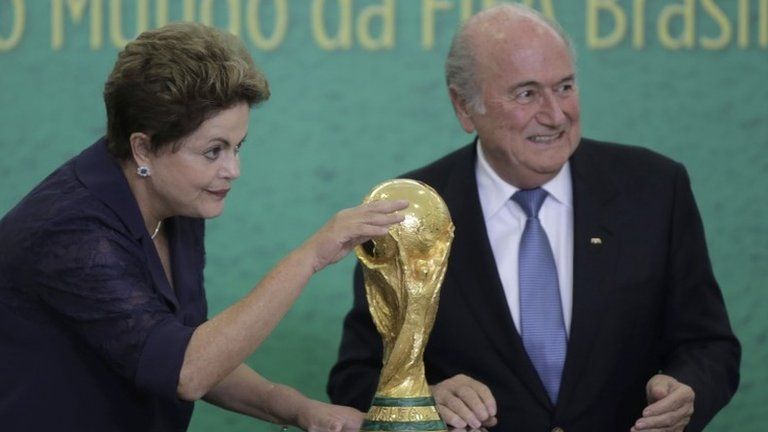 President Dilma Rousseff waves to children at a ceremony where FIFA President Sepp Blatter, right, presented the 2014 World Cup trophy in Brasilia on 2 June
