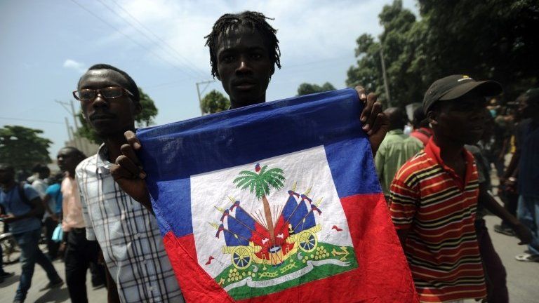 A demonstrator marches with a Haitian national flag during an anti-government protest in Port-au-Prince on 10 June, 2014