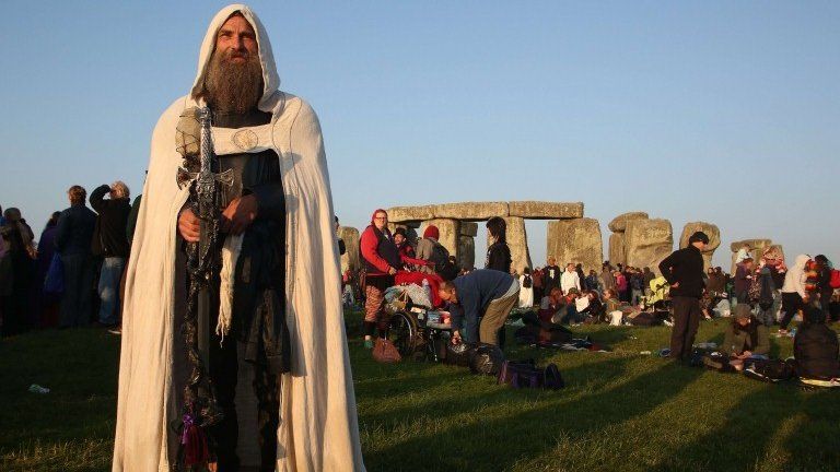 A modern druid named Merlin stands as the sun rises at the prehistoric monument Stonehenge