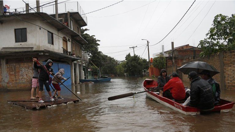 Families use rafts and boats on the flooded roads in the Tacumbu neighborhood of Asuncion, Paraguay. 27/06/2014