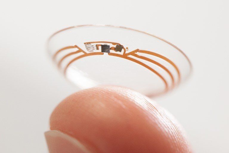 finger holding up Google contact lens prototype