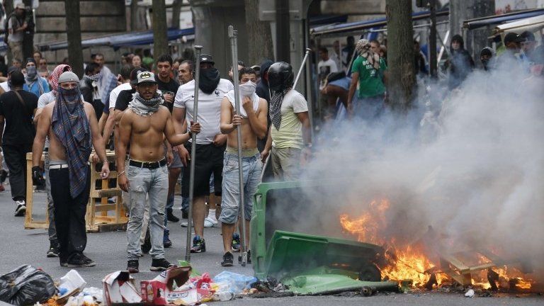 Protesters stand in front of burning bin near the aerial metro station of Barbes-Rochechouart, in Paris, 19 July 2014