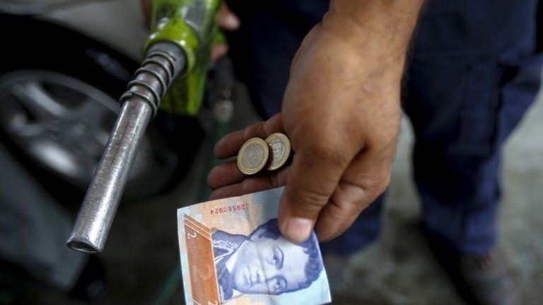 A worker at a petrol station in Venezuela shows the money used to pay for filling the tank