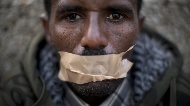 African migrant covers his mouth with tape during a protest in front of the US embassy in Tel Aviv demanding asylum and employment rights in Israel (22 January 2014)